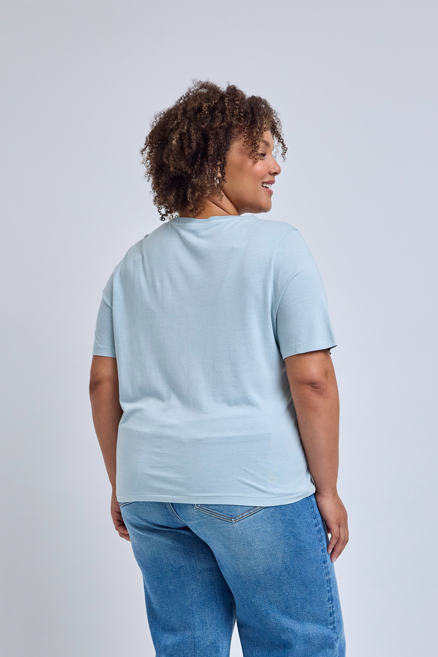 Person wearing a light blue t-shirt and blue jeans on a plain background