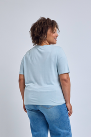 Person wearing a light blue t-shirt and blue jeans on a plain background