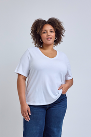 Woman wearing a plain white t-shirt and blue jeans against a light gray background | model-size: 16