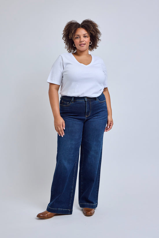Person wearing a white t-shirt and blue jeans on a plain background | model-size: 16