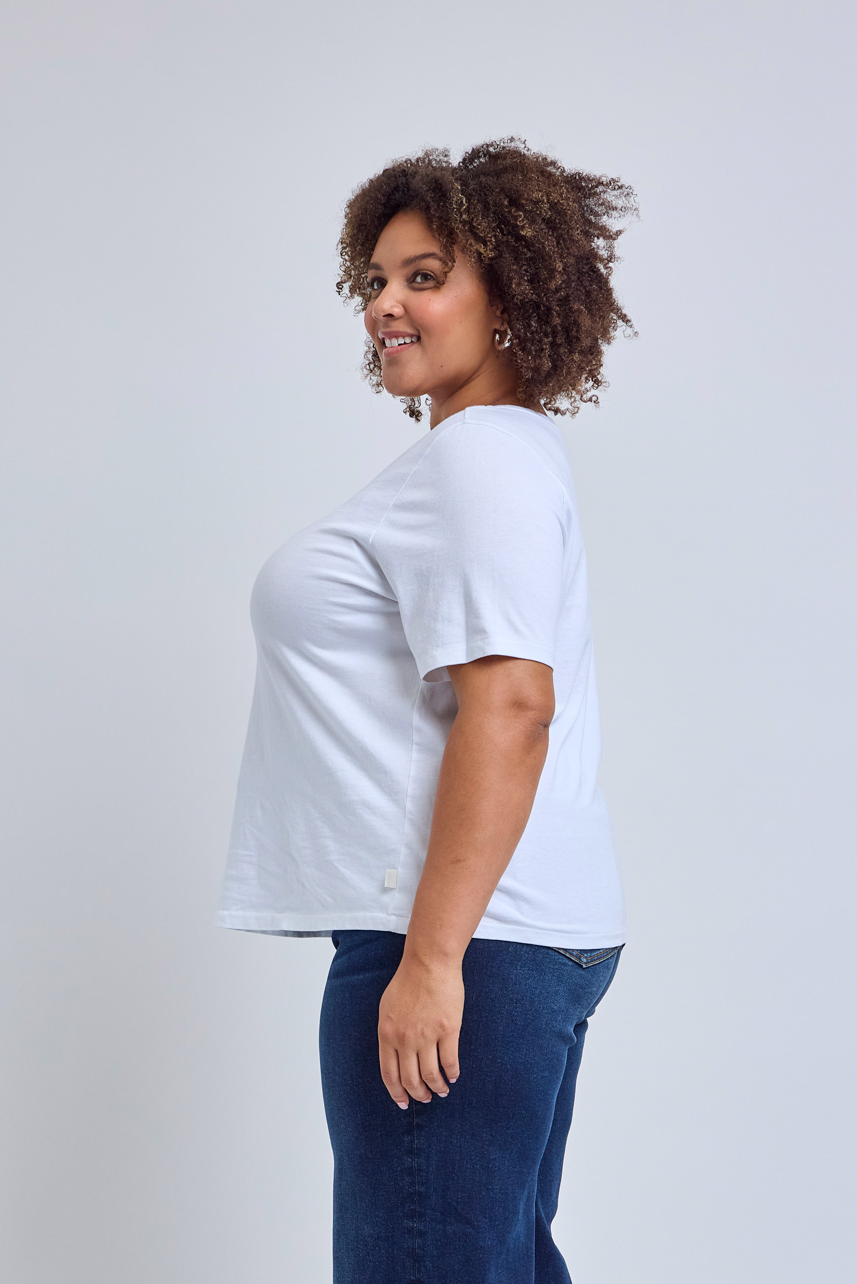 Person wearing a white t-shirt and blue jeans on a plain background
