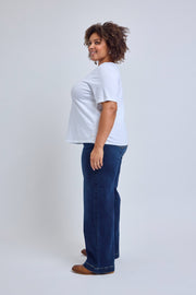 Person wearing a white t-shirt and blue jeans on a plain background