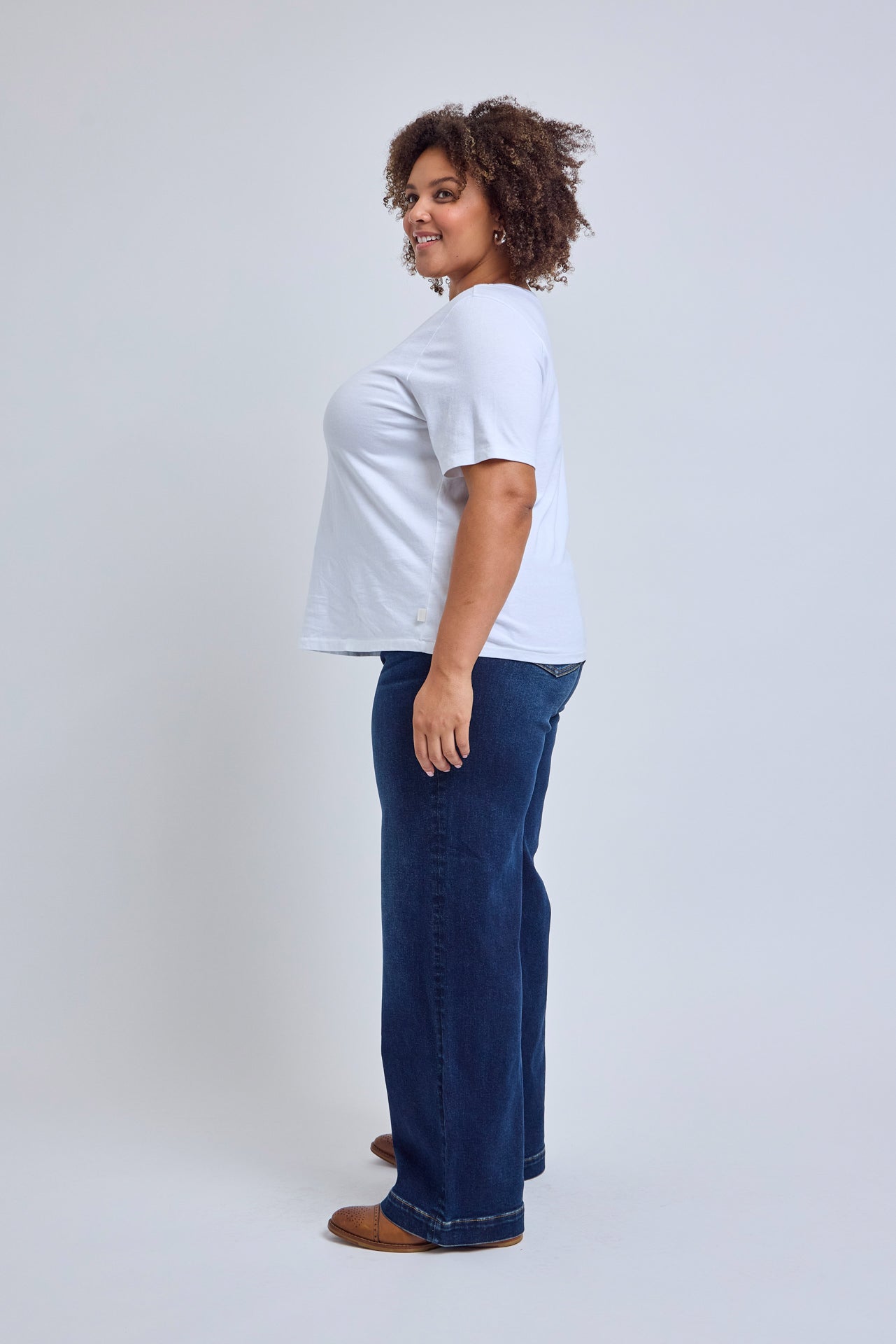 Person wearing a white t-shirt and blue jeans on a plain background