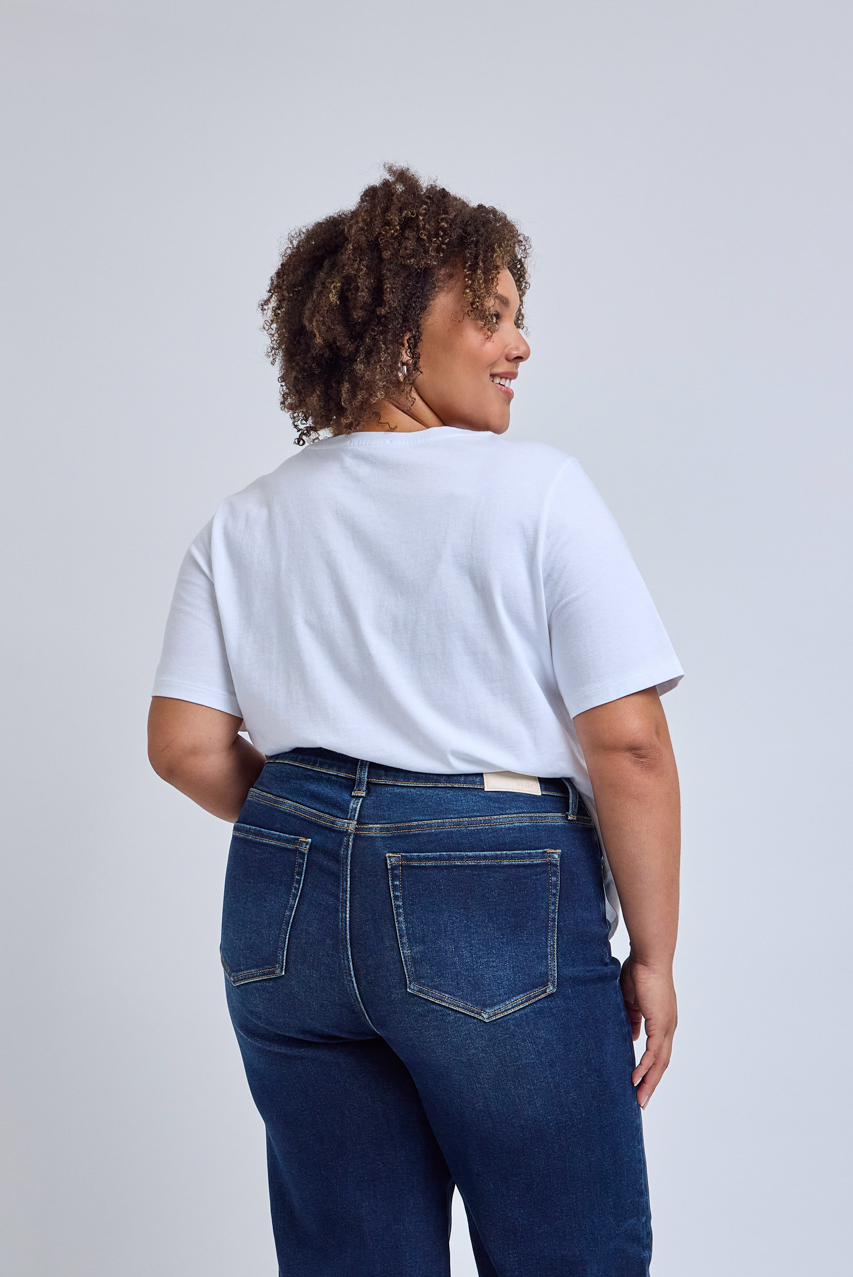 Person wearing a white t-shirt and blue jeans on a plain background