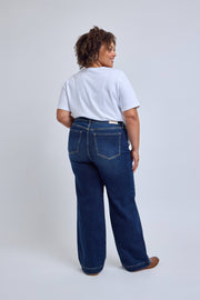Person wearing a white t-shirt and dark blue jeans on a plain background