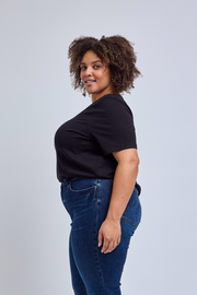 Woman wearing a black t-shirt and blue jeans against a light gray background