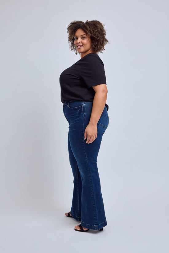Woman wearing a black t-shirt and blue jeans on a white background