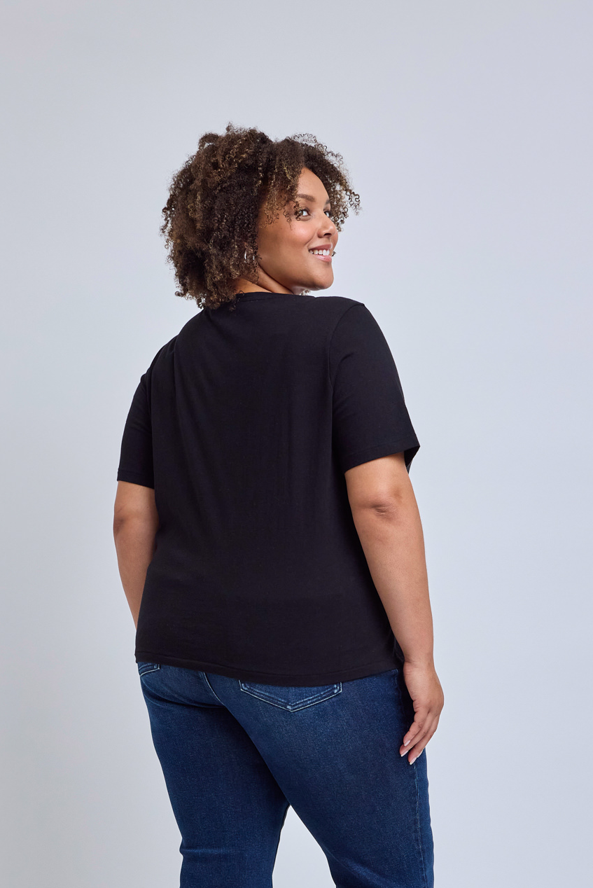 Person wearing a black t-shirt and blue jeans on a light gray background