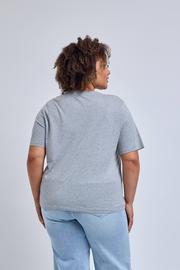 Person wearing a gray t-shirt and light blue jeans on a plain background