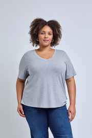 Woman wearing a gray tee and blue jeans against a plain background | model-size: 16