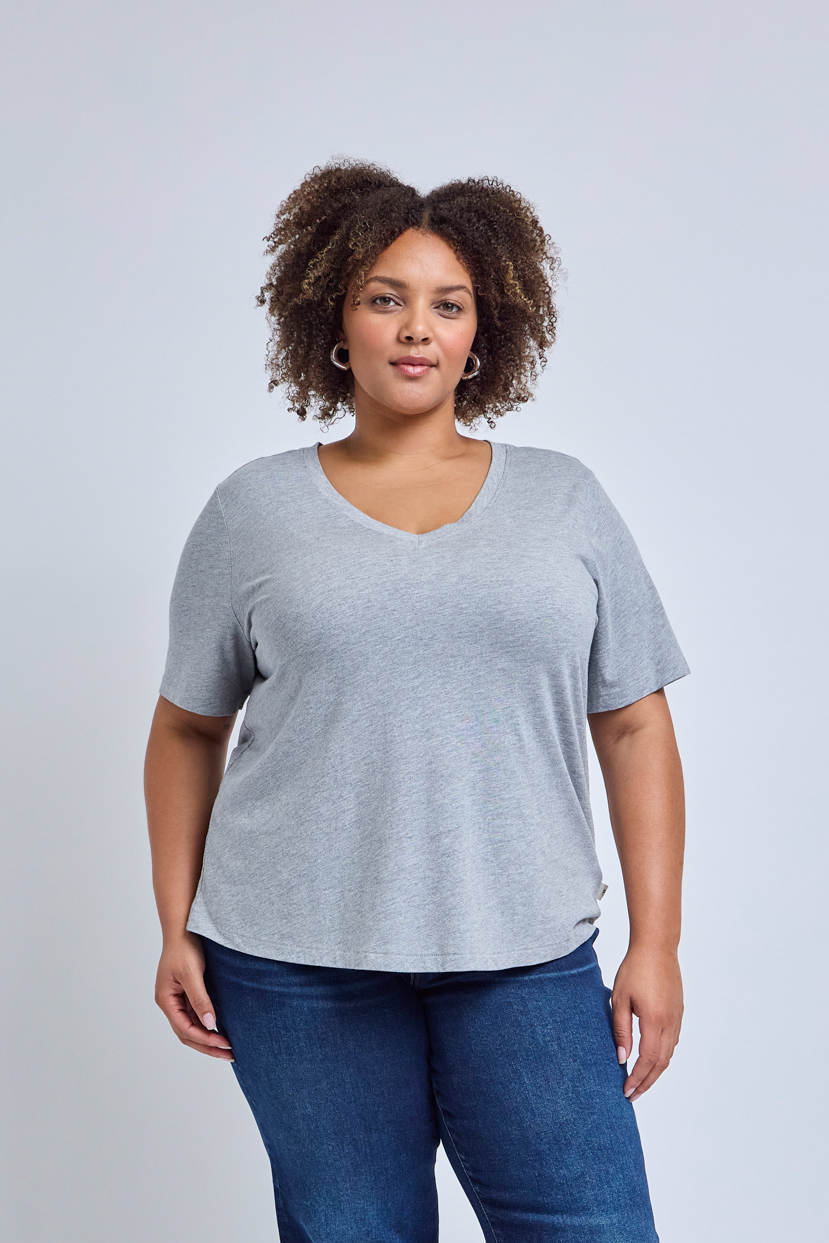 Woman wearing a gray tee and blue jeans against a plain background | model-size: 16
