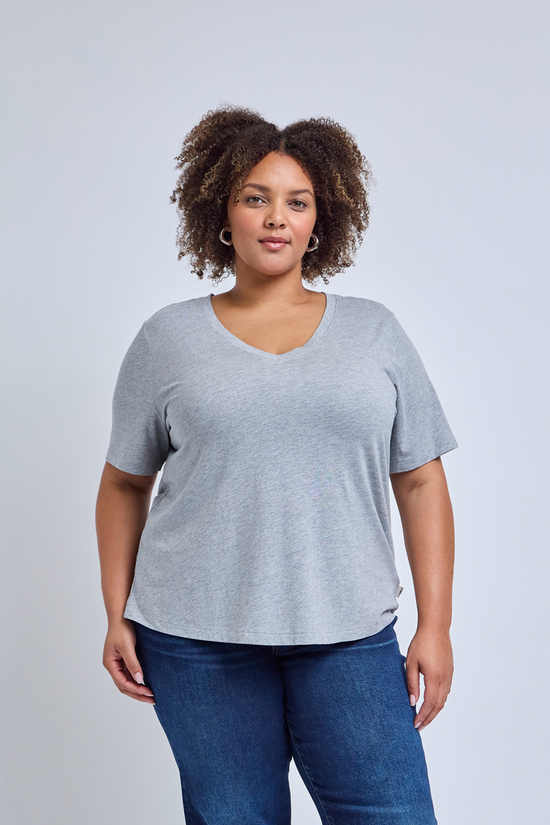 Woman wearing a gray tee and blue jeans against a plain background | model-size: 16