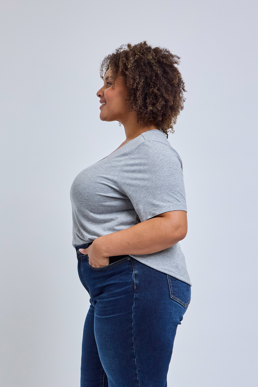 Woman wearing a gray t-shirt and blue jeans against a white background