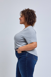 Woman wearing a gray t-shirt and blue jeans against a white background