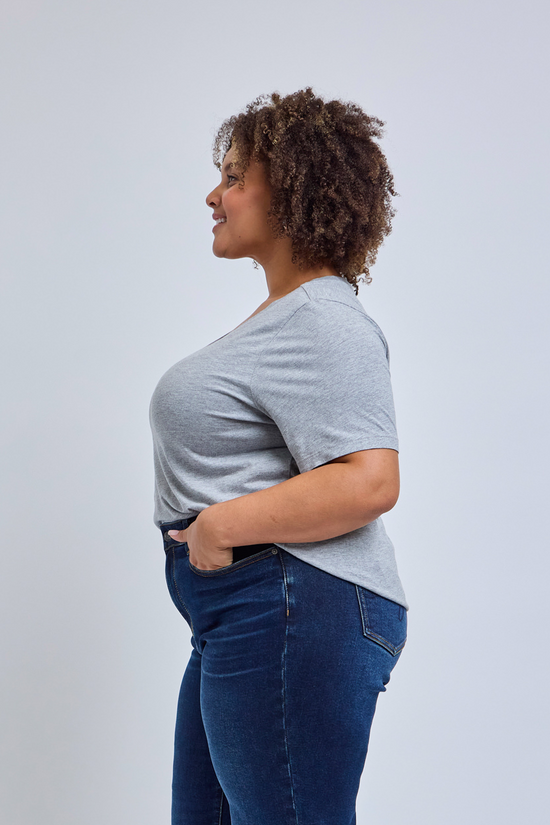 Woman wearing a gray t-shirt and blue jeans against a white background
