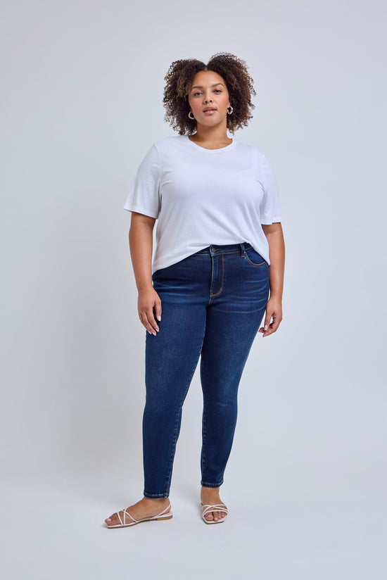 Woman wearing a white t-shirt and blue jeans on a plain background 