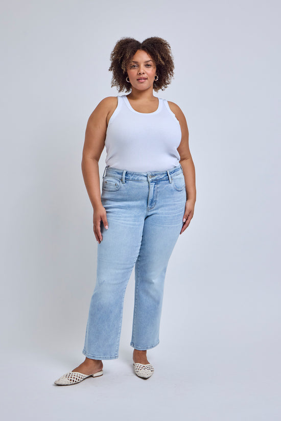 Woman wearing a white tank top and light blue jeans against a plain background | model-size: 16