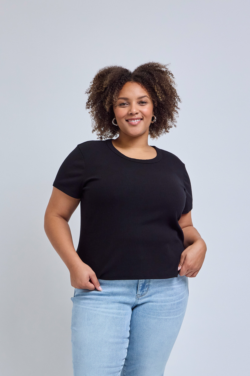 Woman wearing a black t-shirt and light blue jeans against a gray background | model-size: 16