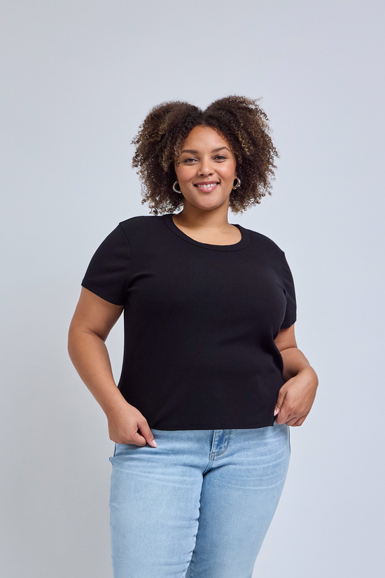 Woman wearing a black t-shirt and light blue jeans against a gray background | model-size: 16