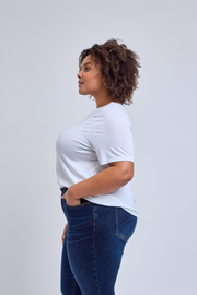 Woman wearing a white t-shirt and blue jeans against a plain background