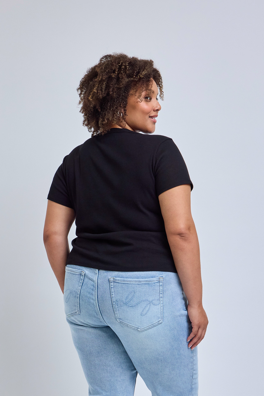 Person wearing a black t-shirt and light blue jeans on a plain background
