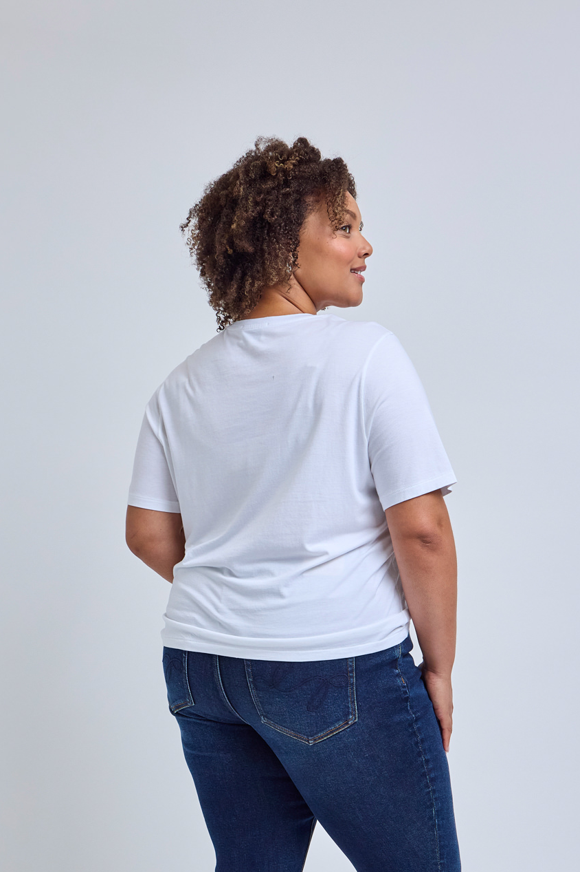 Person wearing a plain white t-shirt and blue jeans on a light gray background