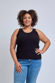 Woman wearing a black tank top and blue jeans against a gray background | model-size: 16