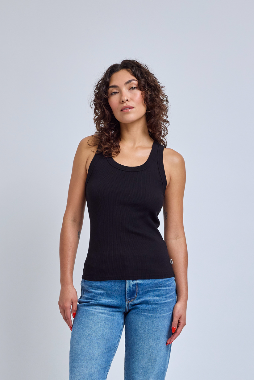 Woman wearing a black tank top and blue jeans against a gray background | model-size: 4