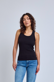 Woman wearing a black tank top and blue jeans against a gray background | model-size: 4