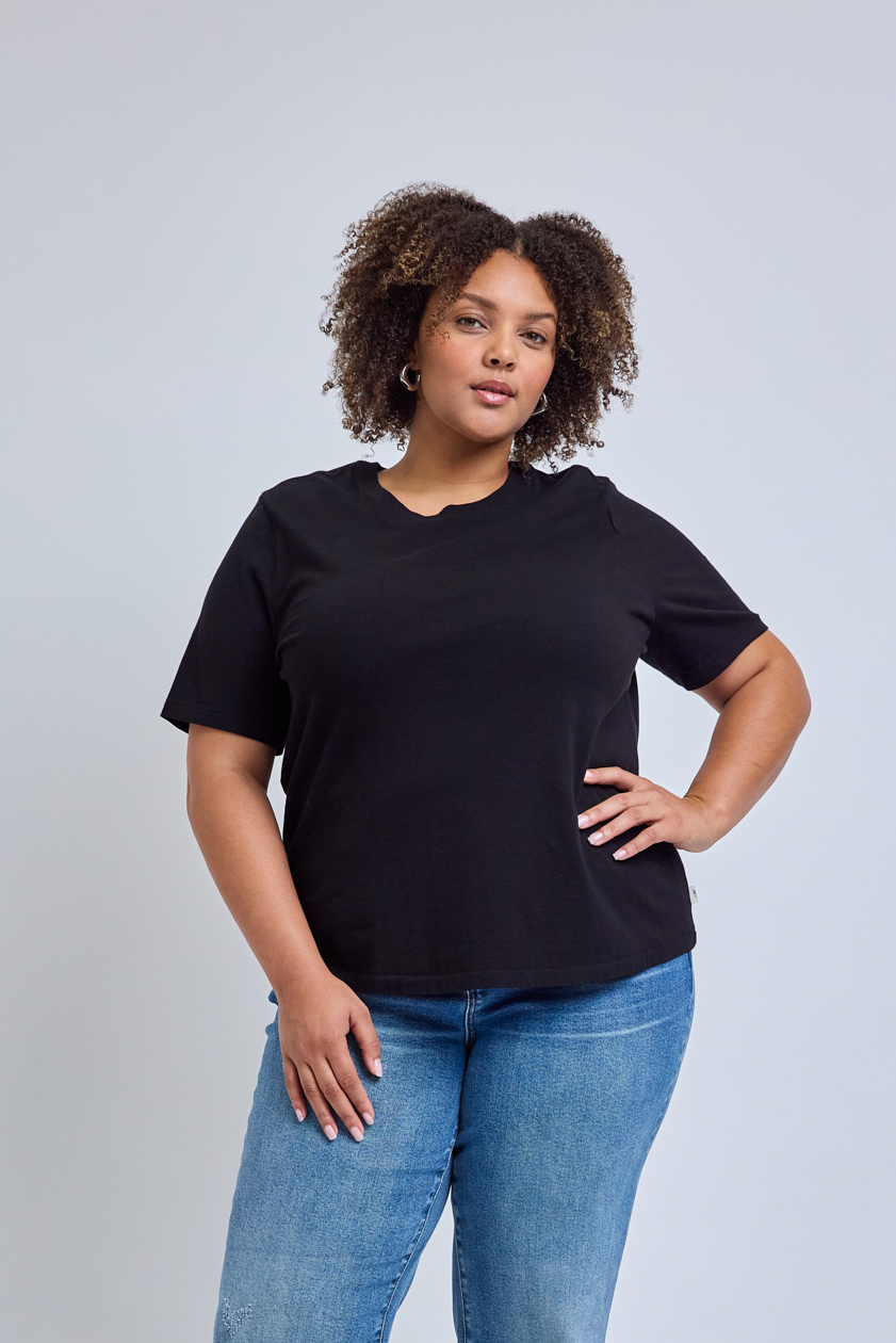 Woman wearing a black t-shirt and blue jeans against a gray background | model-size: 16