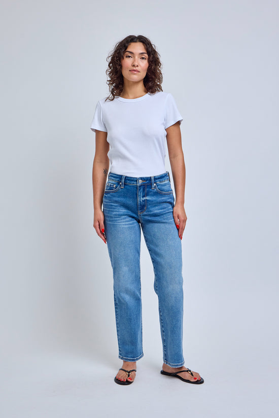 Woman wearing a white t-shirt and blue jeans on a plain background 