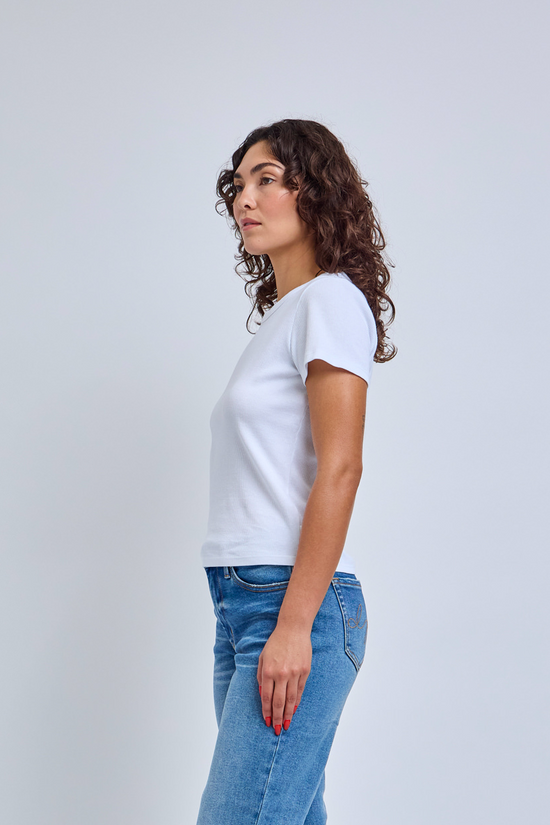 Woman wearing a white t-shirt and blue jeans against a light gray background