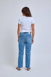 Person wearing blue jeans and a white t-shirt on a plain background