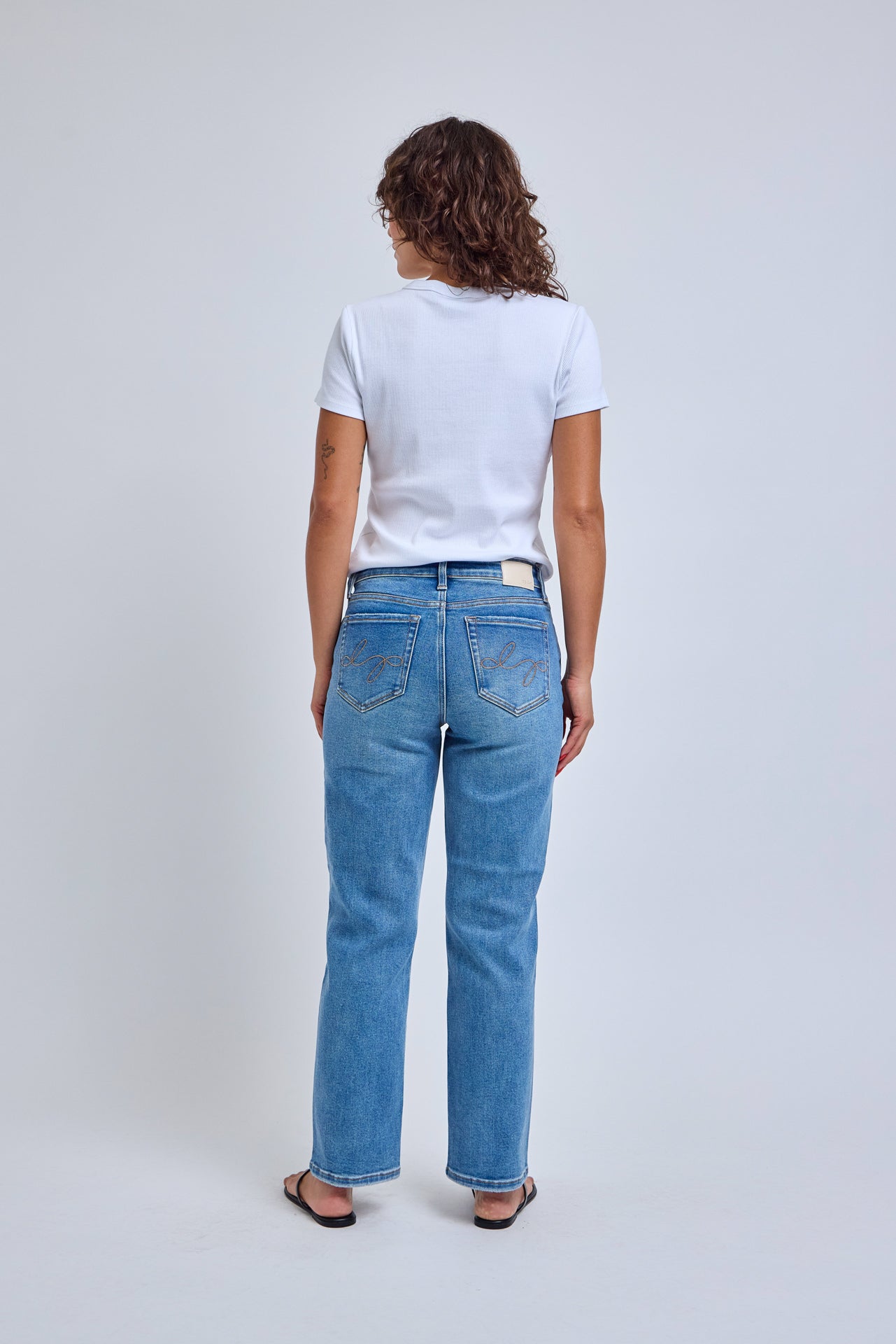 Person wearing blue jeans and a white t-shirt on a plain background