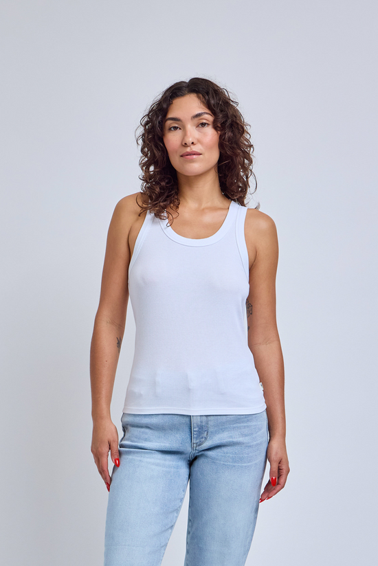 Woman wearing a light blue tank top and jeans against a plain background | model-size: 4