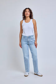Woman wearing a white tank top and light blue jeans on a plain background