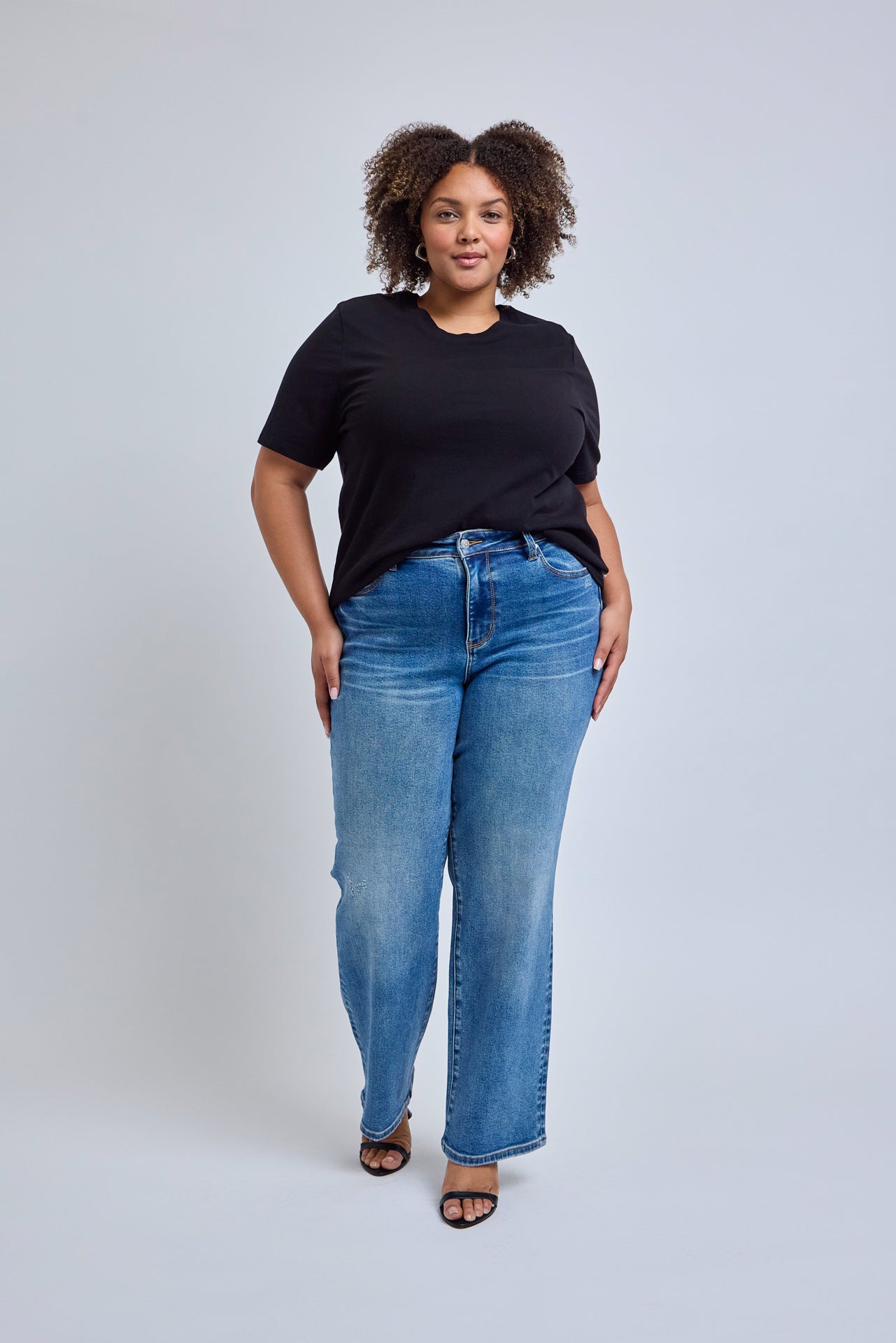 Woman wearing a black t-shirt and blue jeans against a white background | model-size: 16