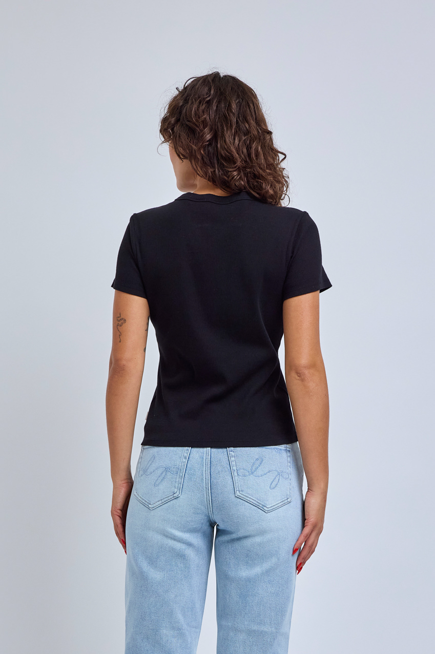 Person wearing a black t-shirt and light blue jeans on a plain background