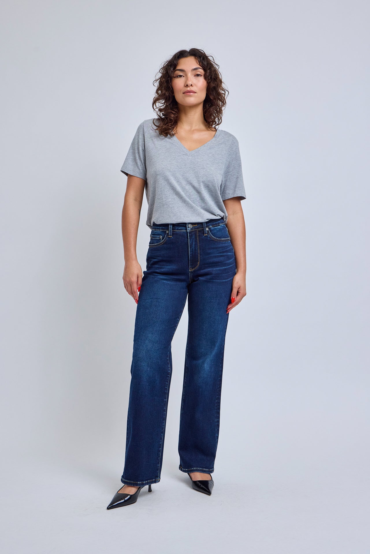 Woman wearing a gray t-shirt and blue jeans on a white background | model-size: 4