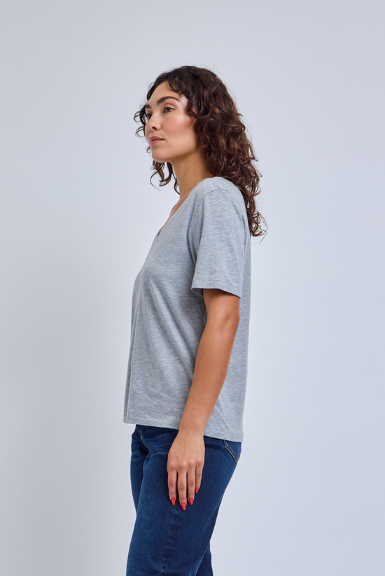 Woman wearing a gray t-shirt and blue jeans against a light gray background