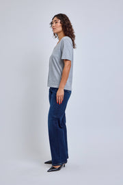 Woman wearing a gray t-shirt and blue jeans on a white background