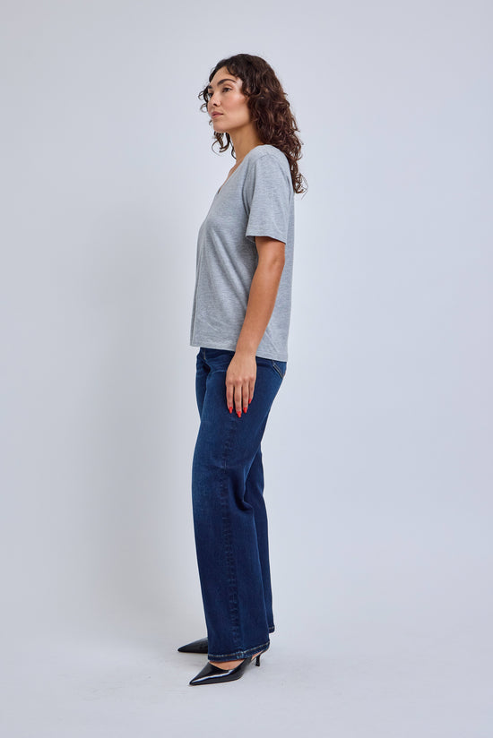 Woman wearing a gray t-shirt and blue jeans on a white background