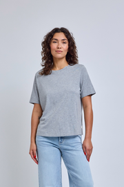 Woman wearing a gray crew neck tee and blue jeans against a plain background | model-size: 4