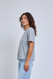 Woman wearing a gray t-shirt and light blue jeans against a white background