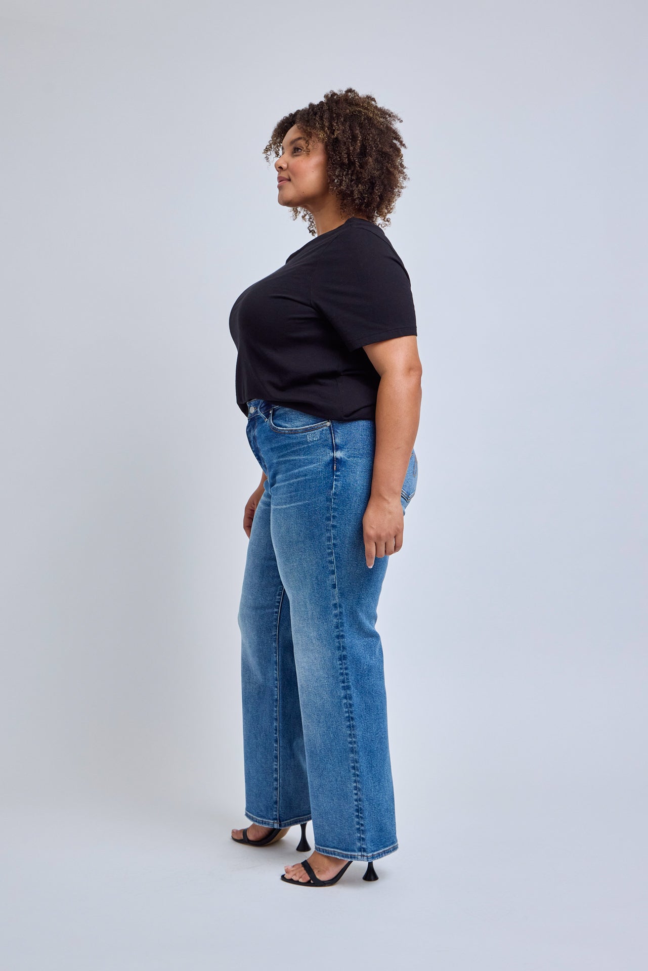 Person wearing a black t-shirt and blue jeans on a white background