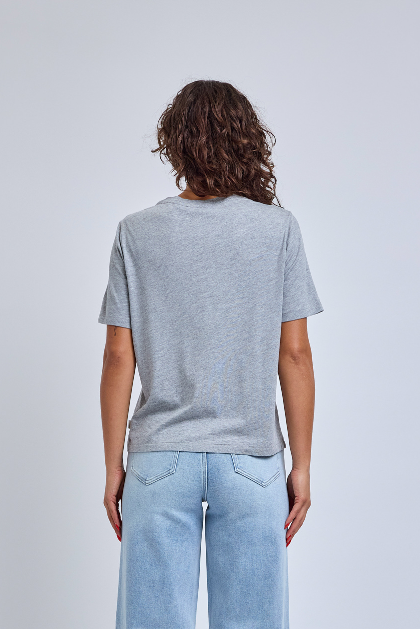 women in heather gray t-shirt standing in front of a gray wall