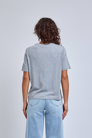 women in heather gray t-shirt standing in front of a gray wall