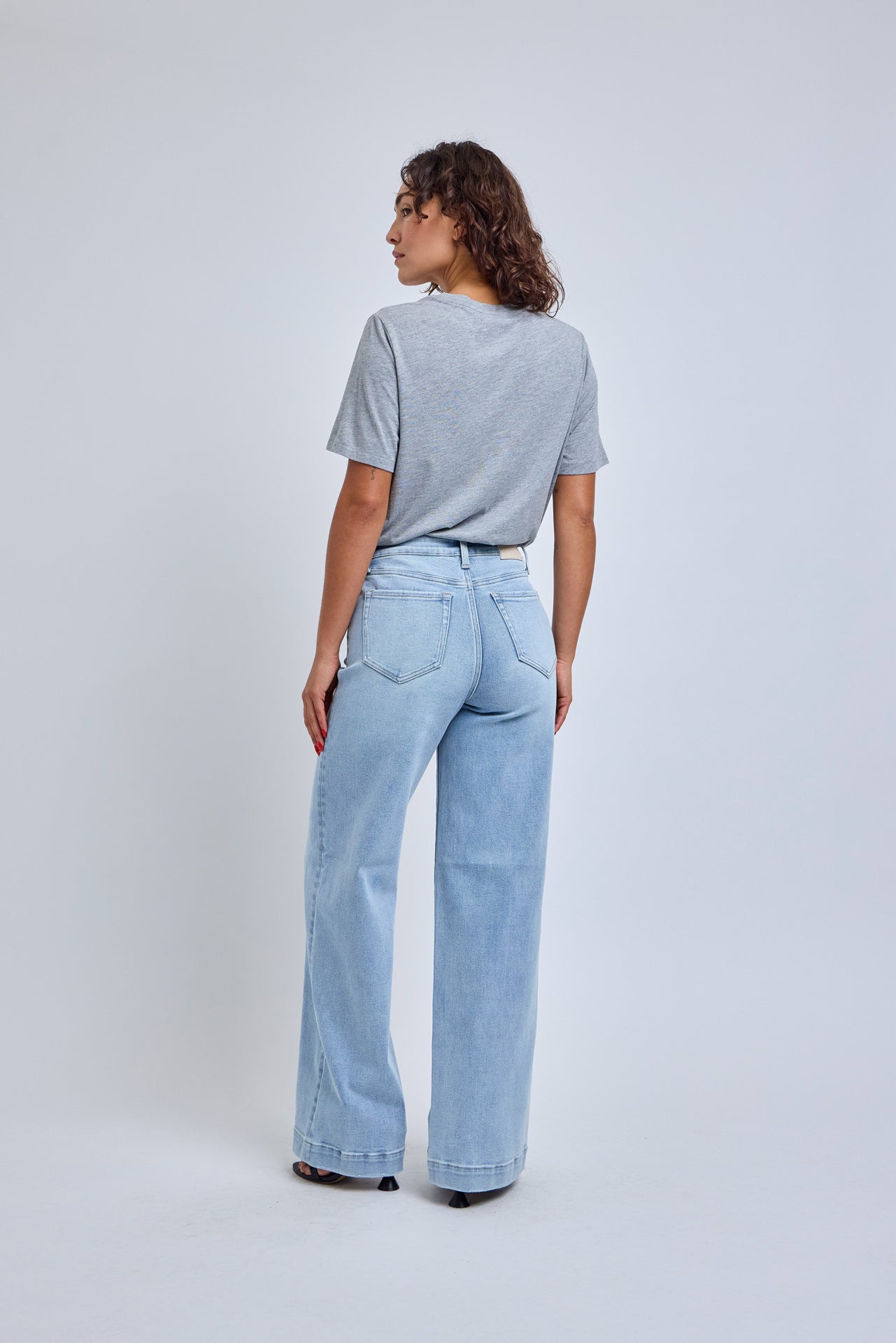 Person wearing light blue jeans and a gray t-shirt on a white background