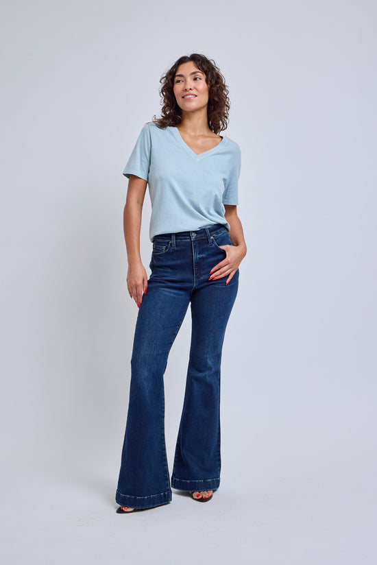 Woman wearing a light blue t-shirt and dark blue jeans on a white background | model-size: 4
