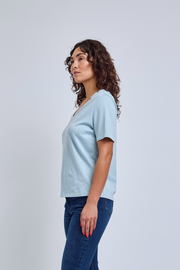 Woman wearing a light blue t-shirt and dark blue jeans against a white background